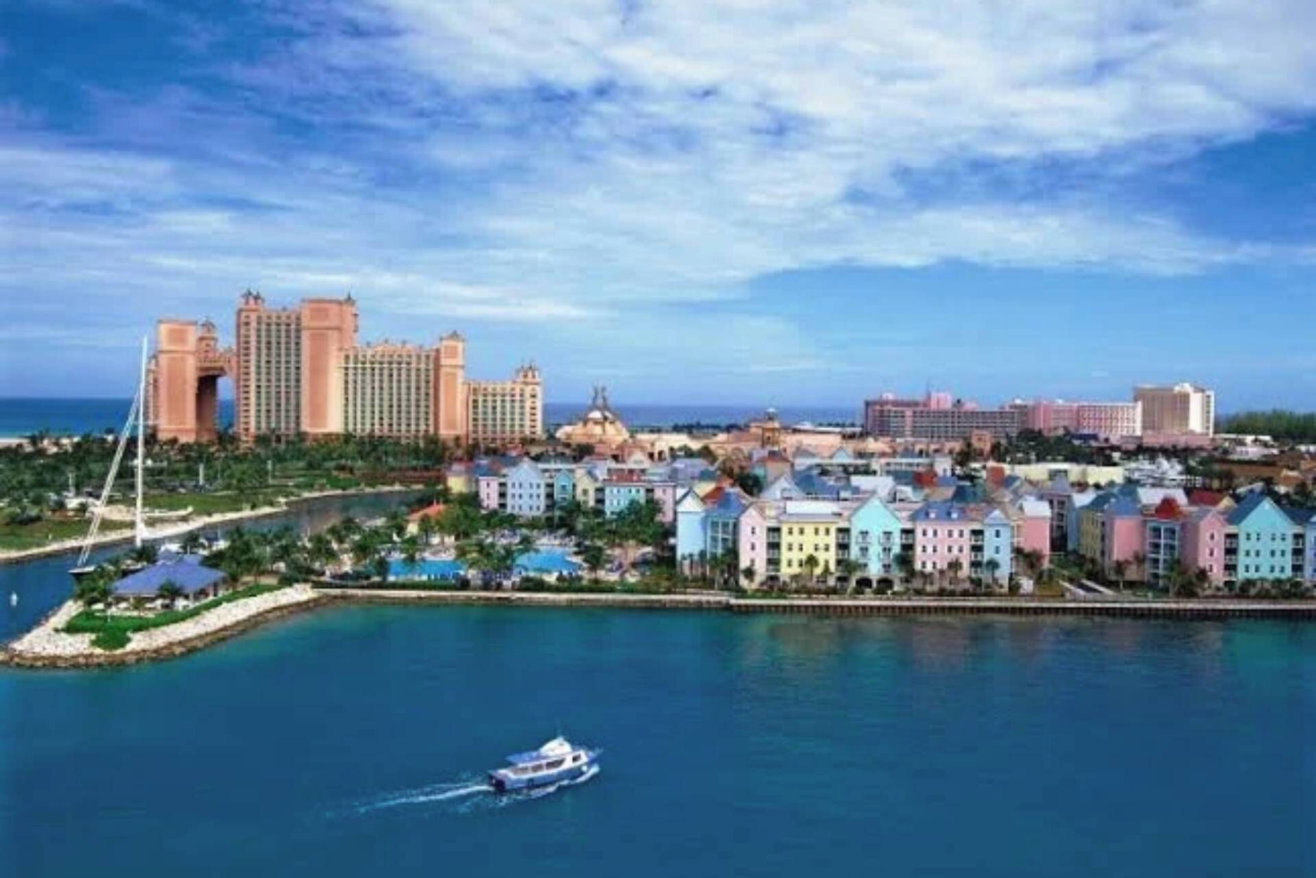 Un paisaje urbano costero con un puerto deportivo, edificios coloridos y un complejo hotelero destacado.