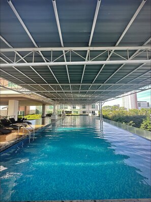 Una amplia piscina interior con techo cubierto, rodeada de sillones de descanso y jardines.