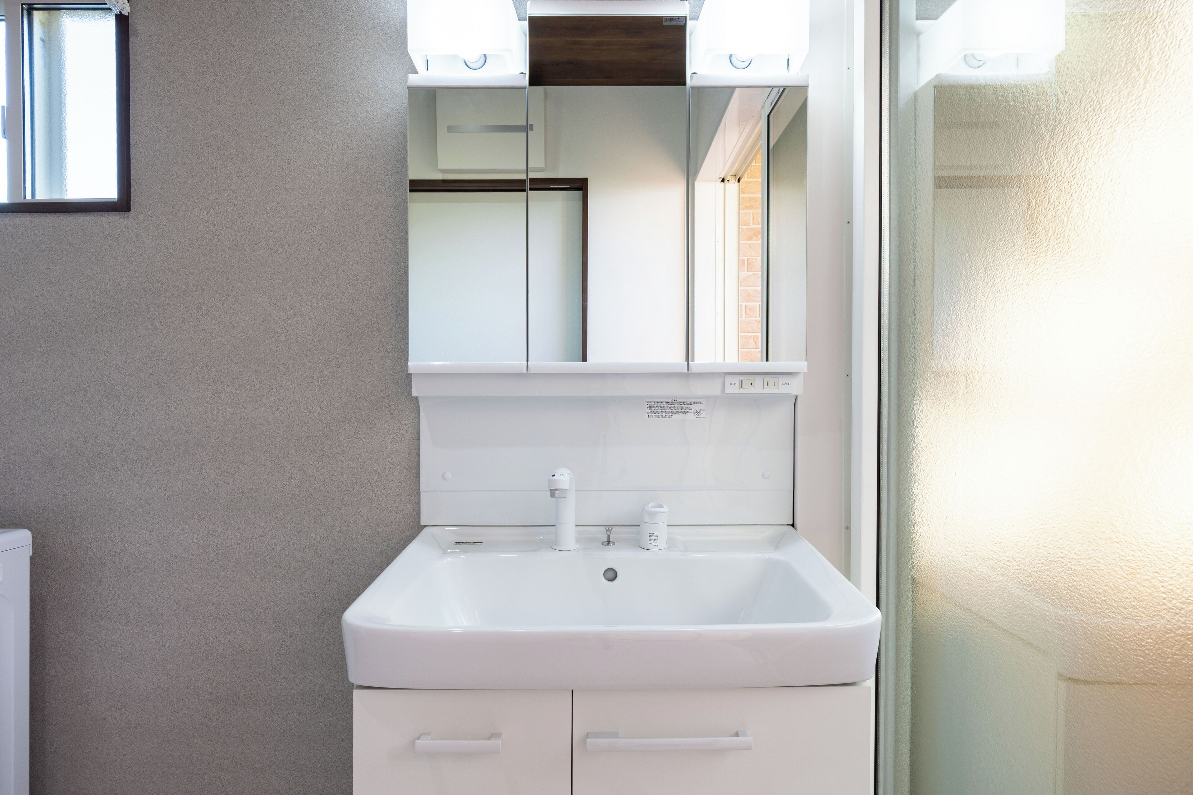 A bathroom with a white sink, a mirror above it, and a cabinet below.