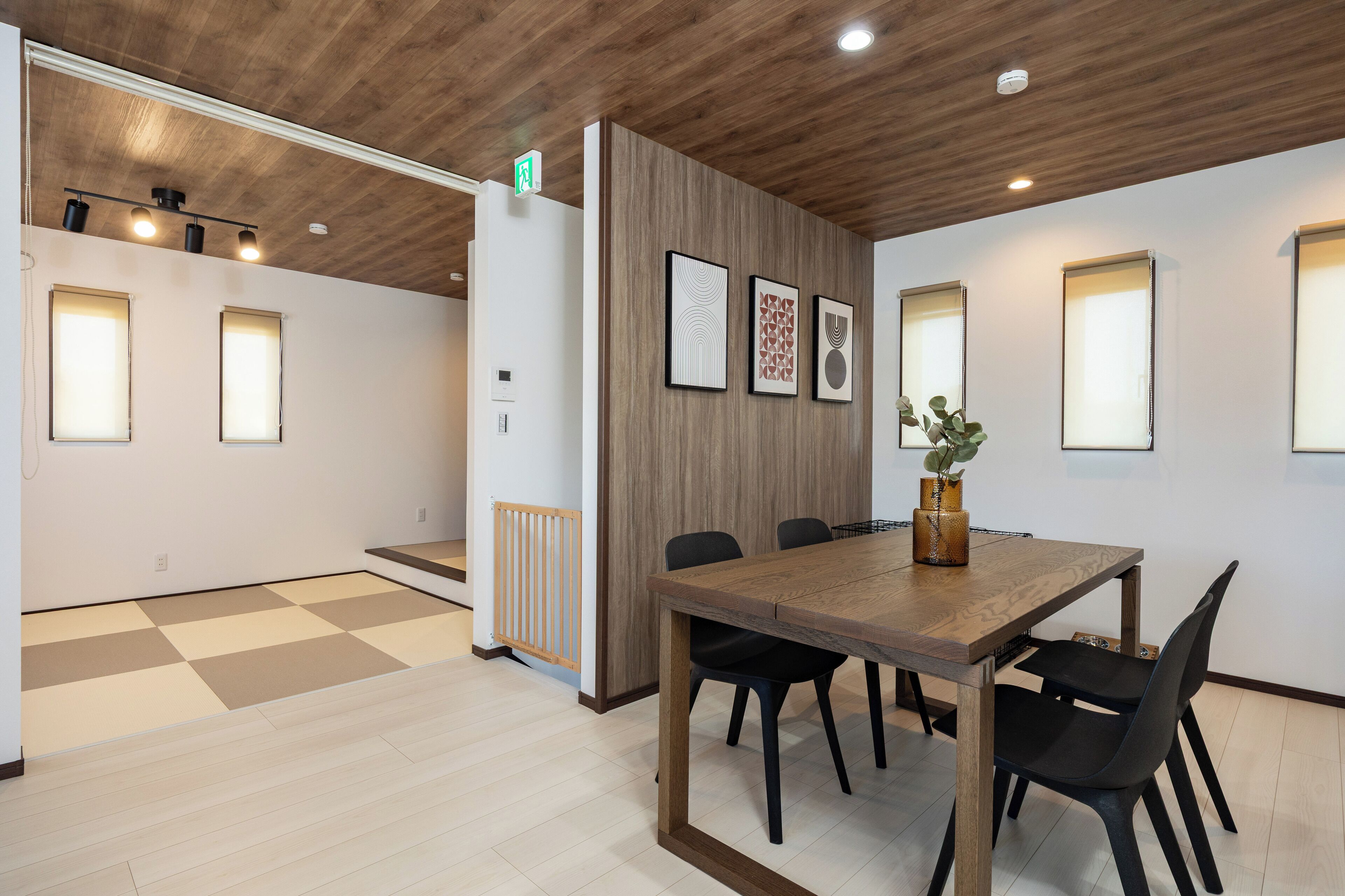 A conference room with a wooden table, black chairs, and framed artwork on the wall.