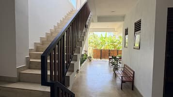 Un escalier avec une rampe en bois menant à un espace extérieur agrémenté d’un banc et de plantes en pot.