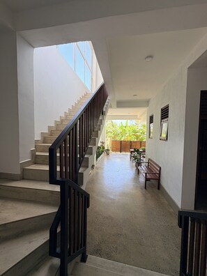 A staircase with a wooden handrail leading to an outdoor area with a bench and potted plants. - Caliza Unawatuna by Sea Cloud (Galle)