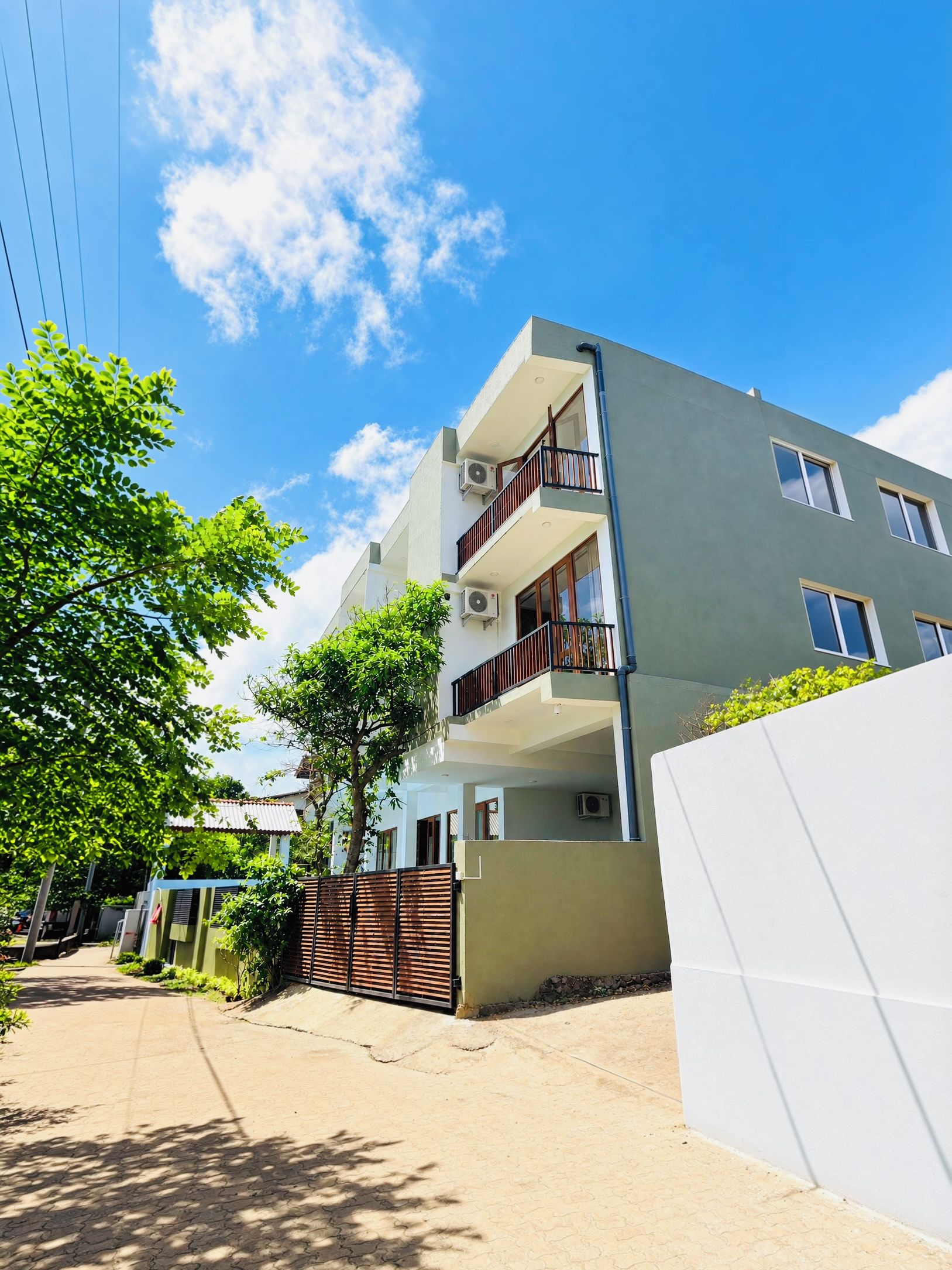 A multi-story residential building with balconies, air conditioning units, and a gated entrance.