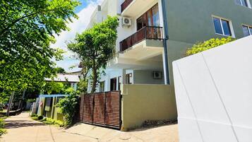 A multi-story residential building with balconies, air conditioning units, and a gated entrance.