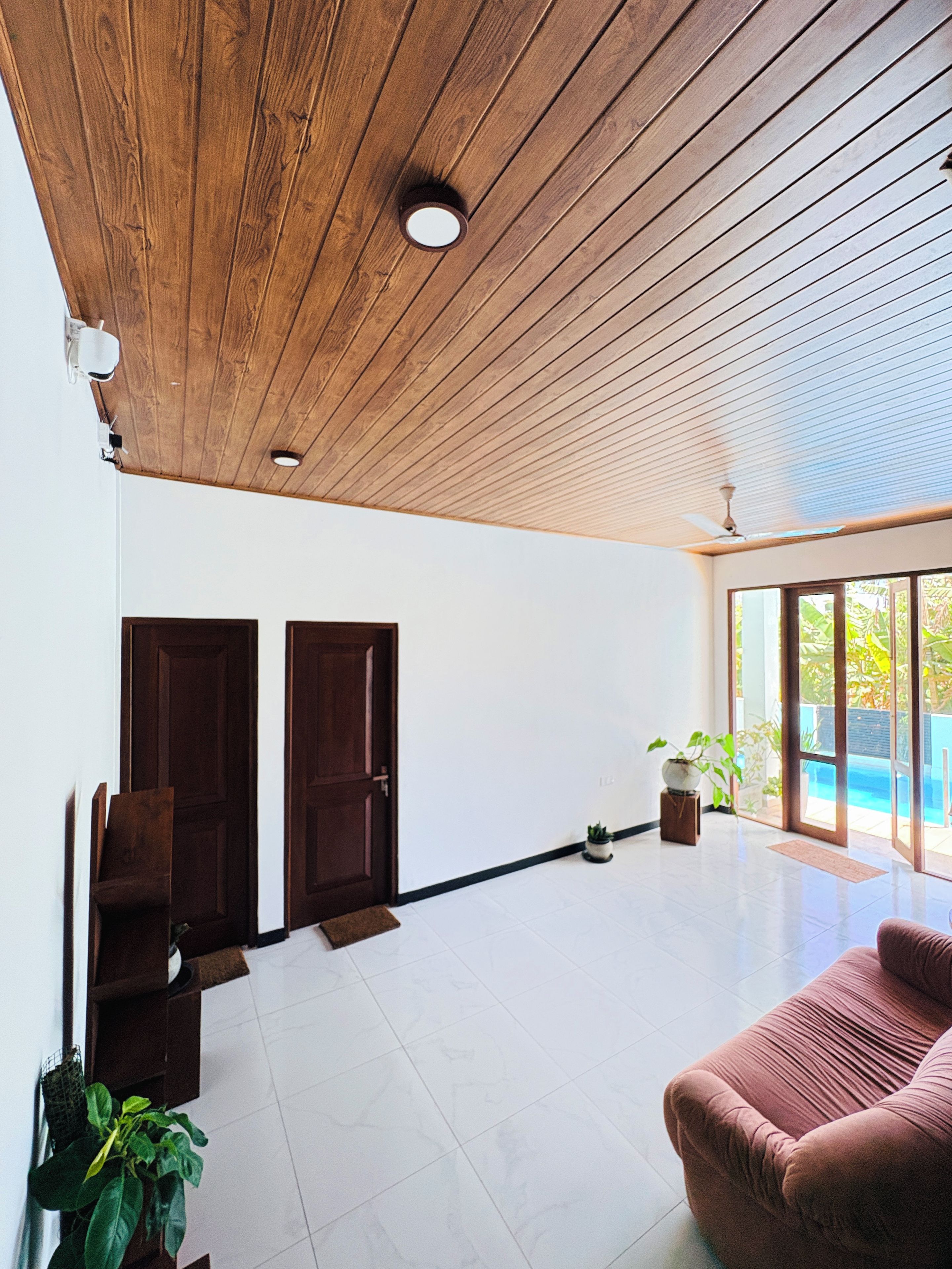 Une pièce spacieuse avec un plafond en bois, une grande fenêtre et une porte.