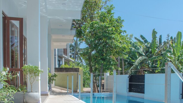 A pool area with a wooden deck, a clear blue pool, and surrounding greenery. - Caliza Unawatuna by Sea Cloud (Galle)