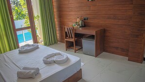 A hotel room with a wooden bed, a desk, and a view of the outdoors. - Caliza Unawatuna by Sea Cloud (Galle)
