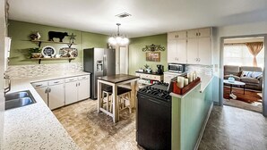 A compact kitchen with a central island, a refrigerator, a microwave, and a sink. - Fenced Yard! Peaceful Retreat in Smithville (Smithville)