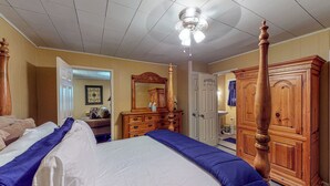 Quarto com cama grande, guarda-roupa de madeira e ventoinha no teto.