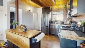 A modern kitchen with wooden beams, stainless steel appliances, and a wooden island. - Boat, Hike, Fish! Summer Cabin Near Lake Arrowhead (Running Springs)