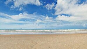 Une plage avec un ciel dégagé et des vagues sur l’océan.