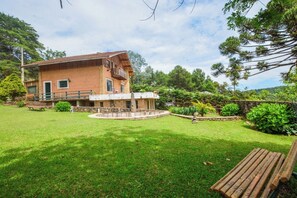 Una casa de ladrillo de dos pisos con fachada de piedra, una fuente de piedra circular y un césped bien cuidado.