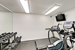 A fitness room with a treadmill, weights, and a digital display. - Resort Perks & Gulf Views: Suntide III - Unit 304 (South Padre Island)