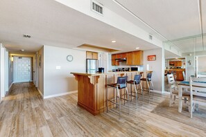 A spacious kitchen with a central island, bar stools, and a dining area with a table and chairs. - All-Suite 3BR, Gulf Views: Suntide III - Unit 208 (South Padre Island)