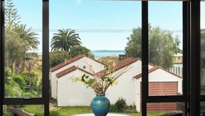 Vista attraverso una finestra di una casa con garage, immersa nel verde e sotto un cielo sereno.