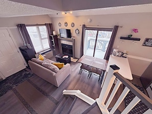 Een compacte woonruimte met een bank, een klein tafeltje, een haard en een balkon met een balustrade.