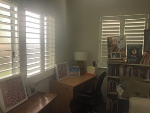 Une pièce comprenant un bureau, une chaise, une bibliothèque et des tableaux encadrés.