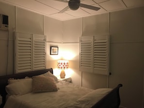 Une chambre à coucher avec un lit, une table de chevet, une lampe et un ventilateur de plafond.