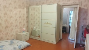 A bedroom with a bed, a wardrobe, a bedside table, and a mirror. - Tabriz iki (Baku)
