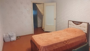 A bedroom with a bed, a door, and a small table. - Tabriz iki (Baku)