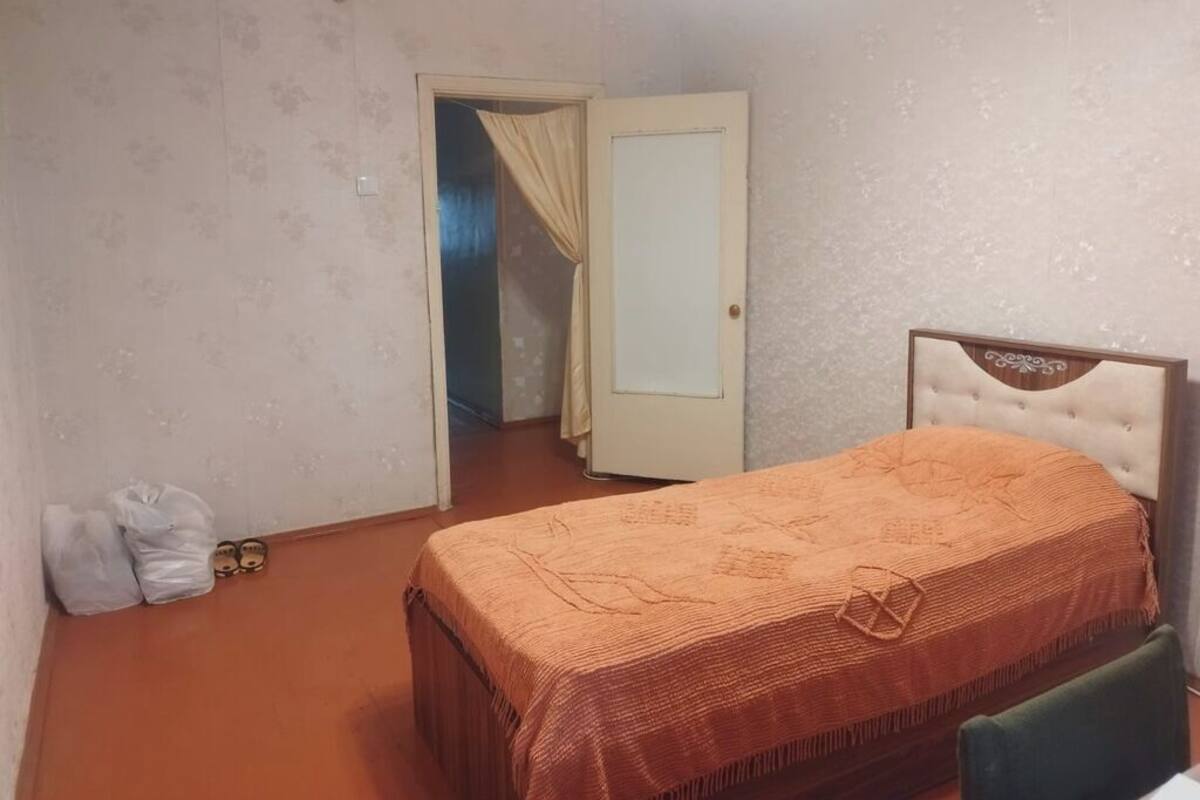A bedroom with a bed, a door, and a small table.