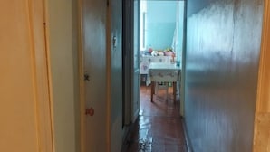 A narrow hallway with wooden flooring leading to a room with a table and chairs. - Tabriz iki (Baku)