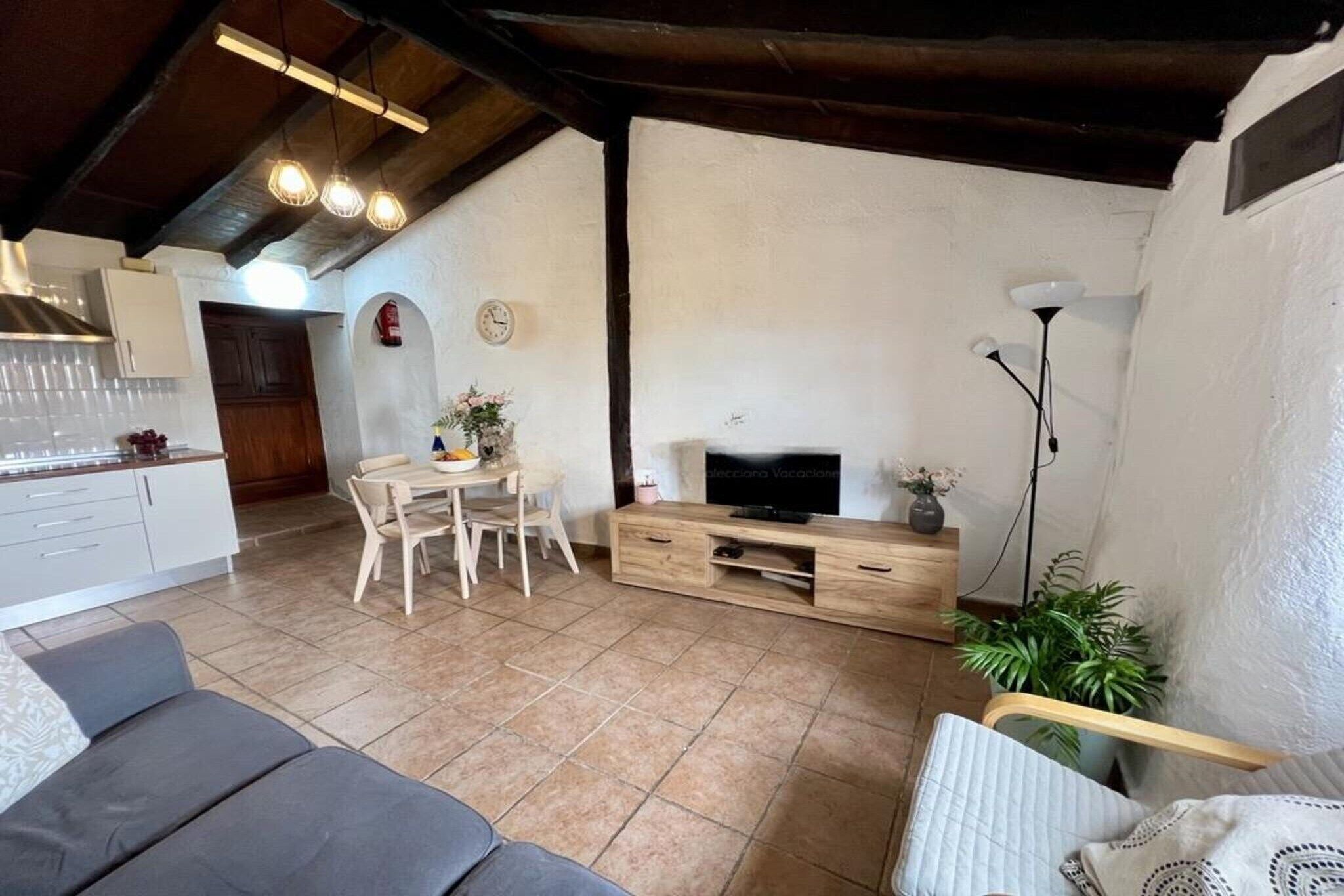 A spacious living area with a dining table, sofa, and TV stand.