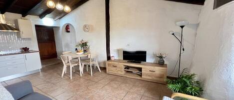 A spacious living area with a dining table, sofa, and TV stand.