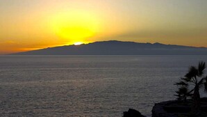 A sunset over a calm sea with a distant mountain range. - El Mango House with private pool (Candelaria)