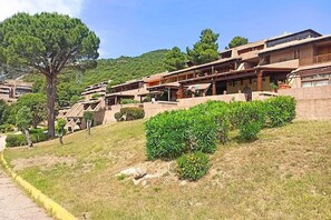 A hillside residential area with terraced houses, a paved path, and green landscaping. - Apartment in Cugnana Verde with garden (Olbia (SS))
