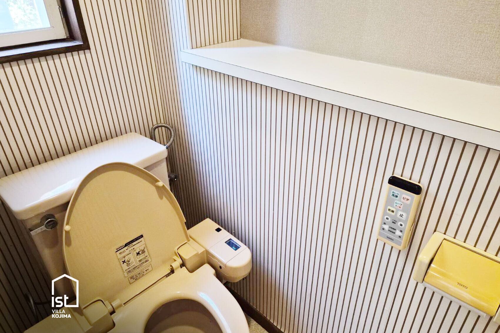 Ein kleines Badezimmer mit Toilette, einem Händetrockner und einem Regal über der Toilette.