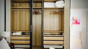Une chambre d’hôtel dotée d’une grande armoire, d’un lit avec du linge de maison blanc et d’un tapis à motifs bleus.
