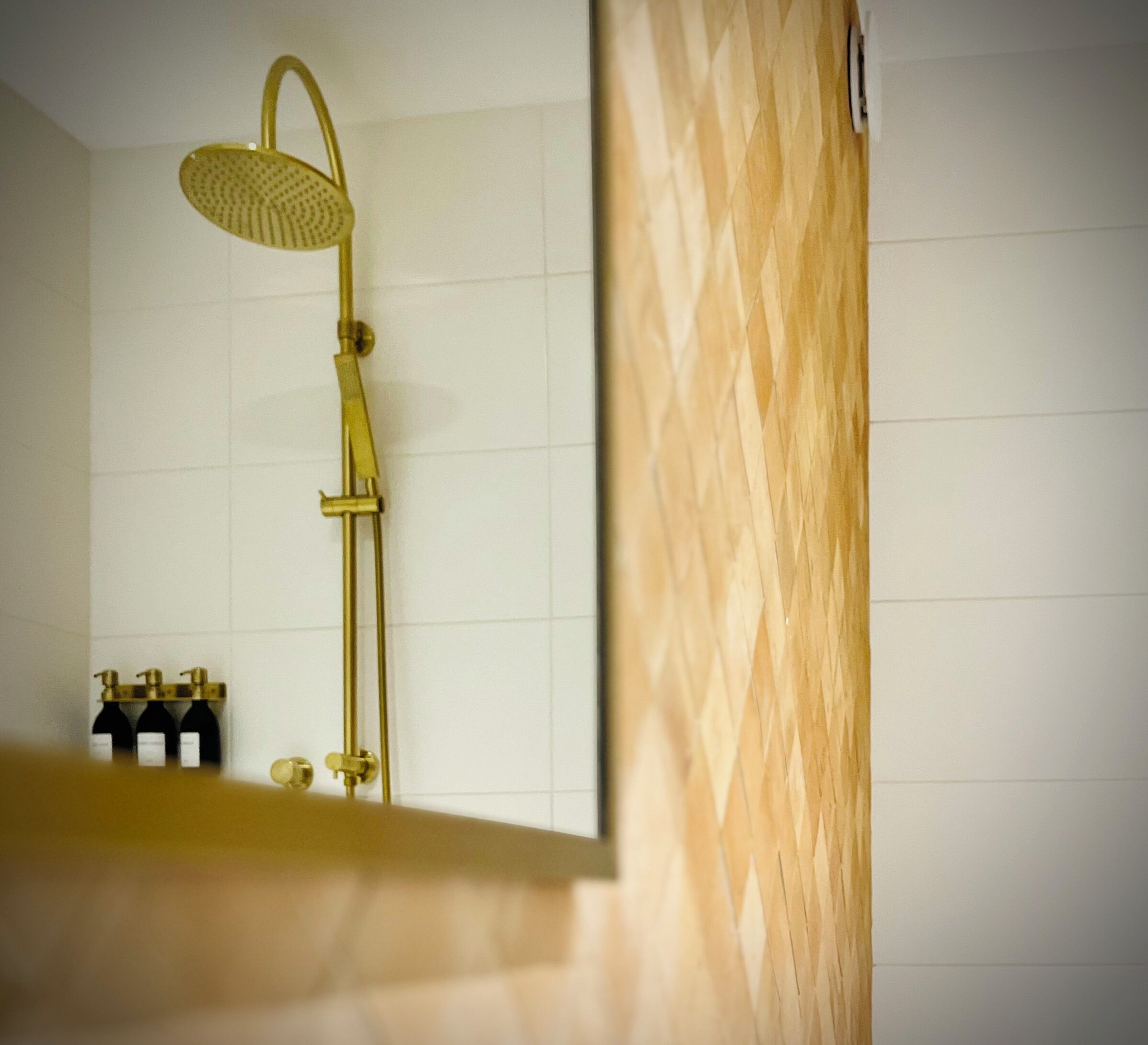 Un baño con cabezal de ducha dorado y un revestimiento de pared de madera.