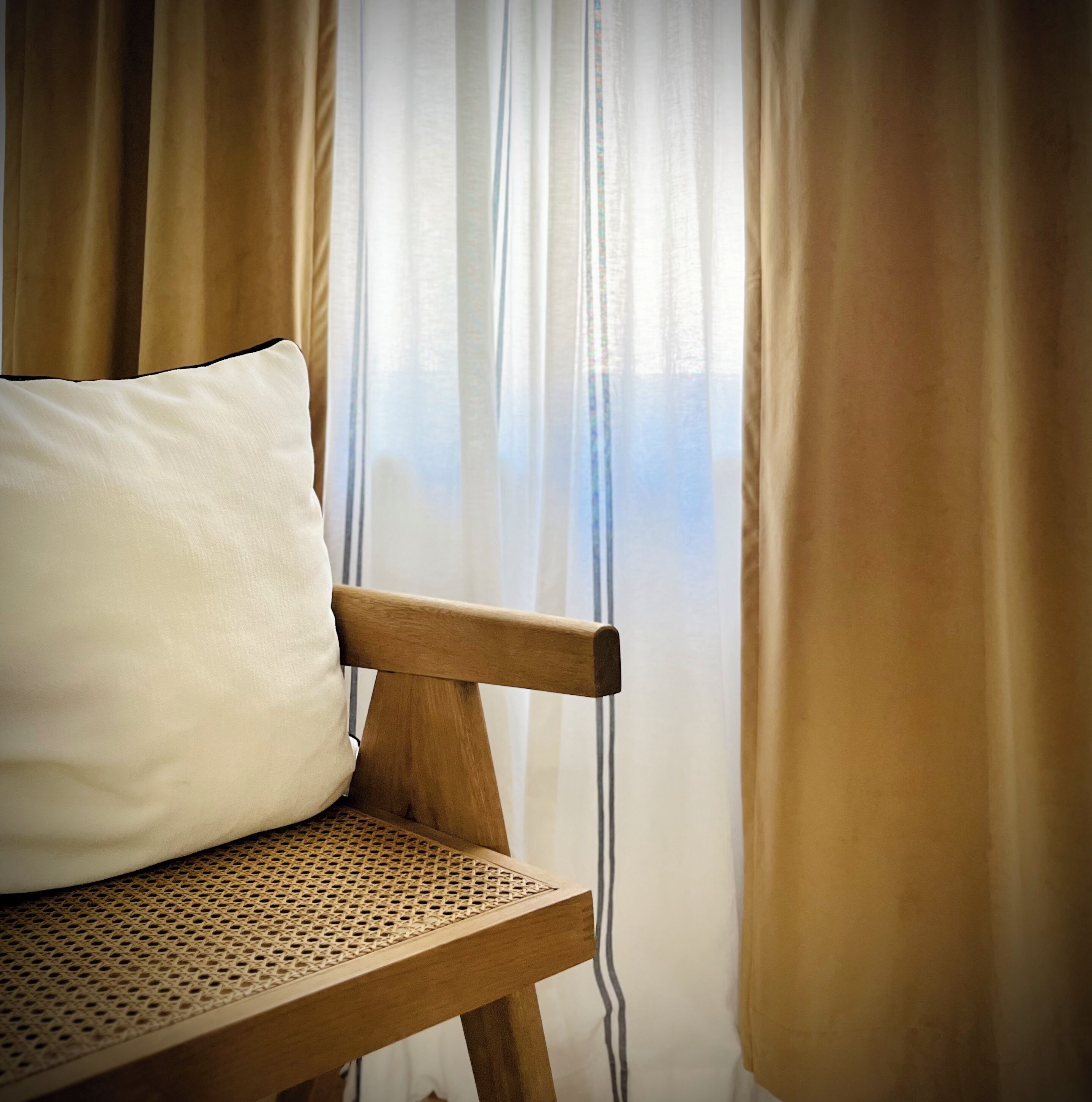 A wooden chair with a woven seat and a white pillow.