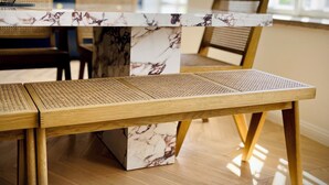 Une cuisine moderne avec un plan de travail en marbre, des chaises en bois et un motif de parquet en chevrons.