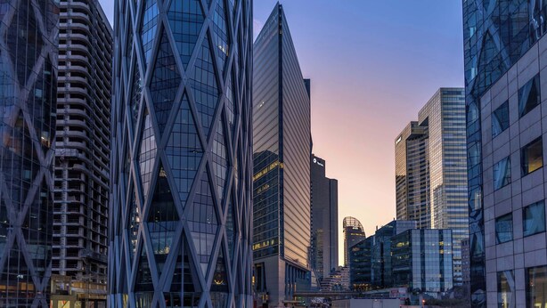 A cityscape with modern high-rise buildings, including a distinctive triangular structure and a building with a 'TOTAL' sign. - Quiet and cosy 2BR in Nanterre - Near La Defense (Nanterre)