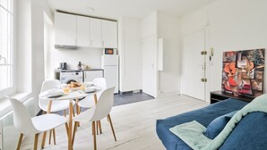 A modern living space with a dining area, kitchen, and a blue sofa. - Quiet and cosy 2BR in Nanterre - Near La Defense (Nanterre)