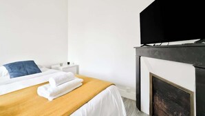 A hotel room with a bed, a nightstand, a television, and a fireplace. - Quiet and cosy 2BR in Nanterre - Near La Defense (Nanterre)