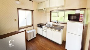 A compact kitchen with white cabinets, a microwave, a sink, and a window.
