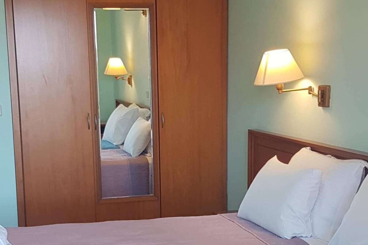 Ein Schlafzimmer mit Bett, Kleiderschrank, Spiegel und einer Wandlampe.
