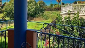 A covered outdoor area with a blue pillar, a round table, and two chairs. - Poseidon Apartments (Agios Gordios)