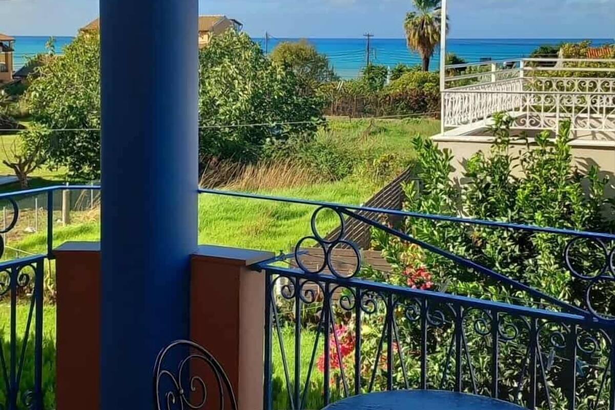 Ein überdachter Außenbereich mit einer blauen Säule, einem runden Tisch und zwei Stühlen.