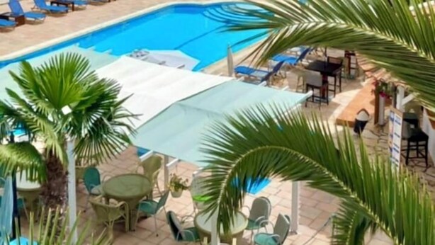 A hotel with a swimming pool surrounded by palm trees and lounge chairs. - Poseidon Apartments (Agios Gordios)