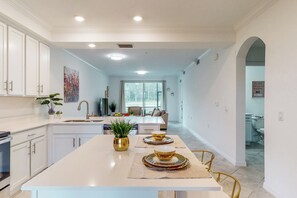 Une cuisine moderne avec des meubles blancs, un îlot central et un coin repas avec des chaises.