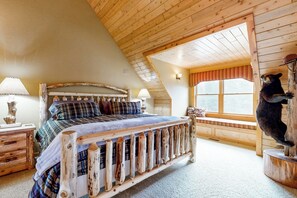 Ein Schlafzimmer mit einem Holzbett, einem Fenster mit Blick und einer Bärenskulptur.