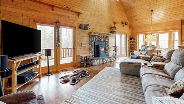 A cozy cabin interior with a fireplace, a television, and a comfortable seating area. - Steps to Sturgeon River! Dog-Friendly Nature Haven (Vanderbilt)