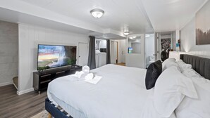 A modern hotel room with a large bed, a flat-screen TV, a vanity with a mirror, and a door leading to a bathroom. - ❃Free Parking ❃ 2 King Beds ❃ Fenced Yard❃ ~ Floyd's Freedom ~ (Alexandria)