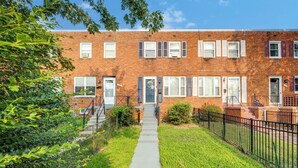 A brick apartment building with a central entrance, multiple windows, and a small front yard with a sidewalk and a metal fence. - ❃Free Parking ❃ 2 King Beds ❃ Fenced Yard❃ ~ Floyd's Freedom ~ (Alexandria)