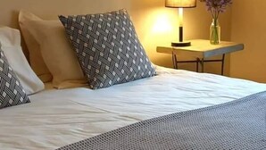 A neatly made bed with patterned pillows, a bedside table with a lamp and vase, and a dark towel on the bed. - Self-catering farmhouse on working farm, a peaceful retreat outside of Underberg (Underberg)