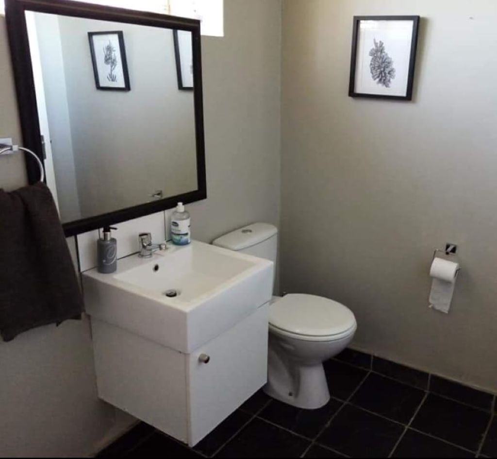 Une salle de bain avec un lavabo blanc, des toilettes et deux tableaux encadrés accrochés au mur.